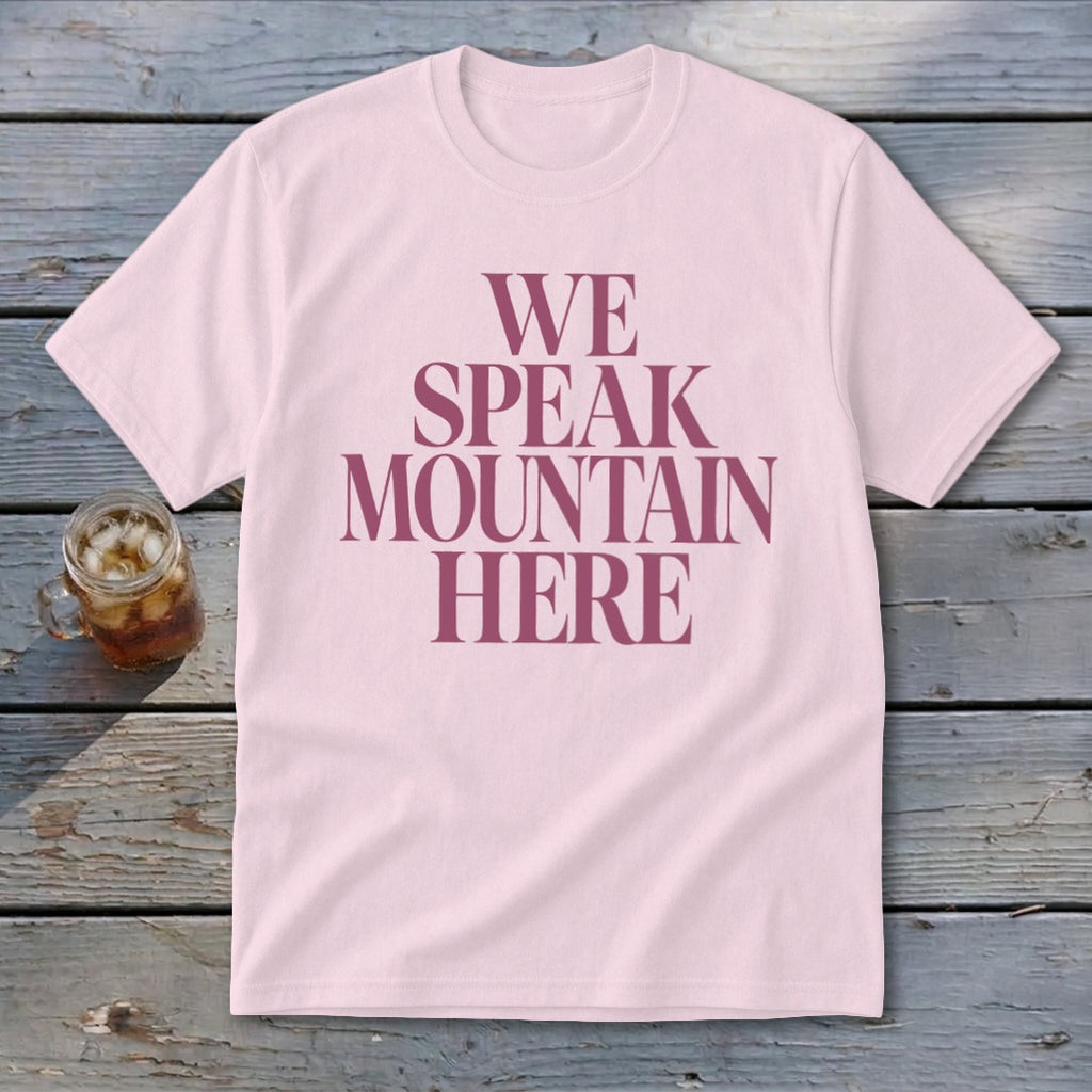 Light pink t-shirt with "WE SPEAK MOUNTAIN HERE" text in dark pink.