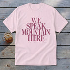 Light pink t-shirt with "WE SPEAK MOUNTAIN HERE" text in dark pink.