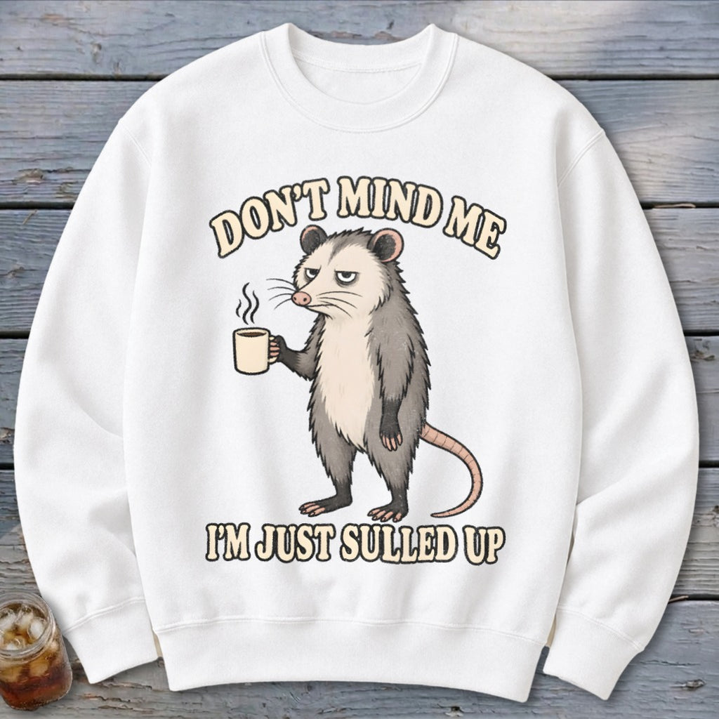 White sweatshirt with a grumpy opossum holding a coffee mug and text.