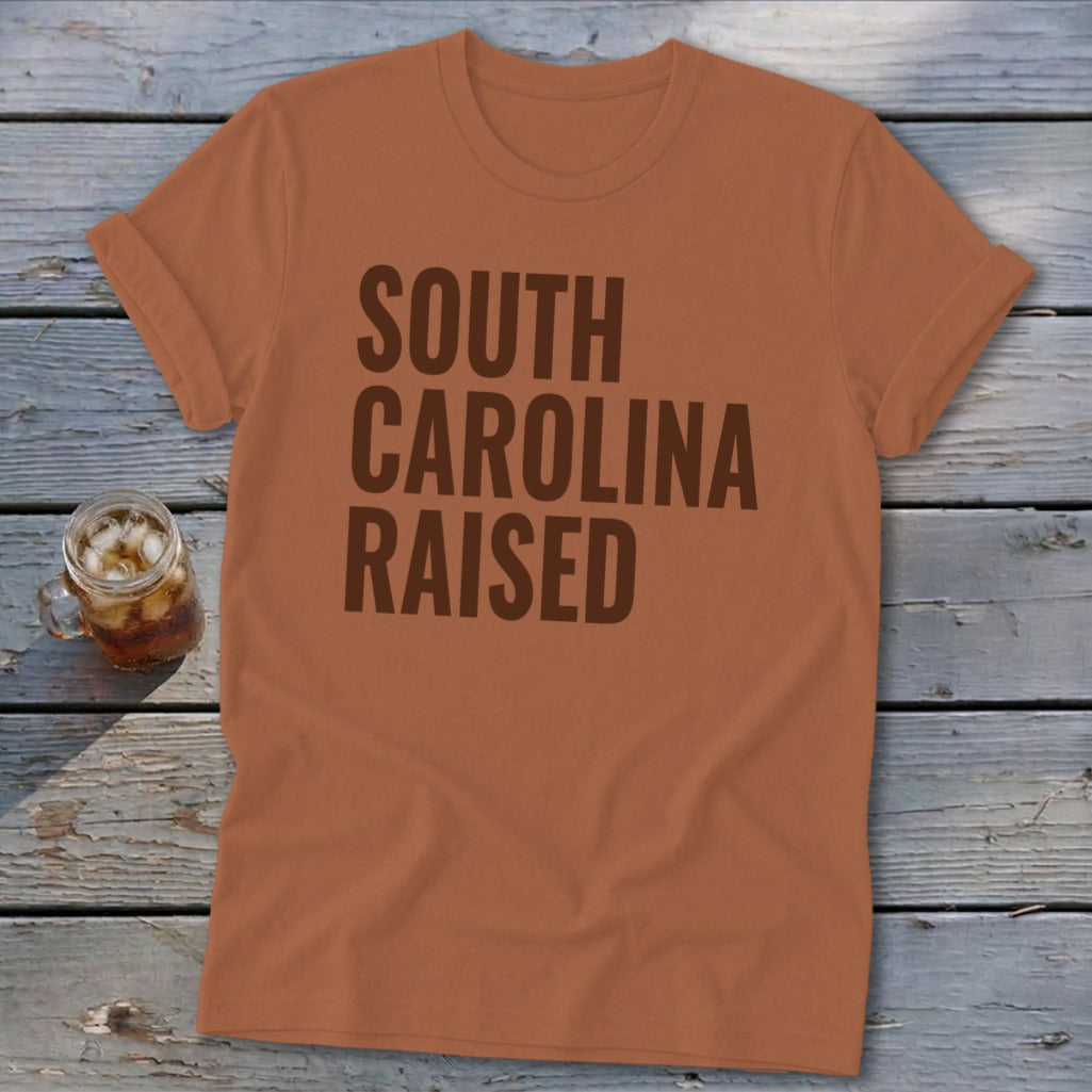 Brown t-shirt with "SOUTH CAROLINA RAISED" text and a glass of iced tea.