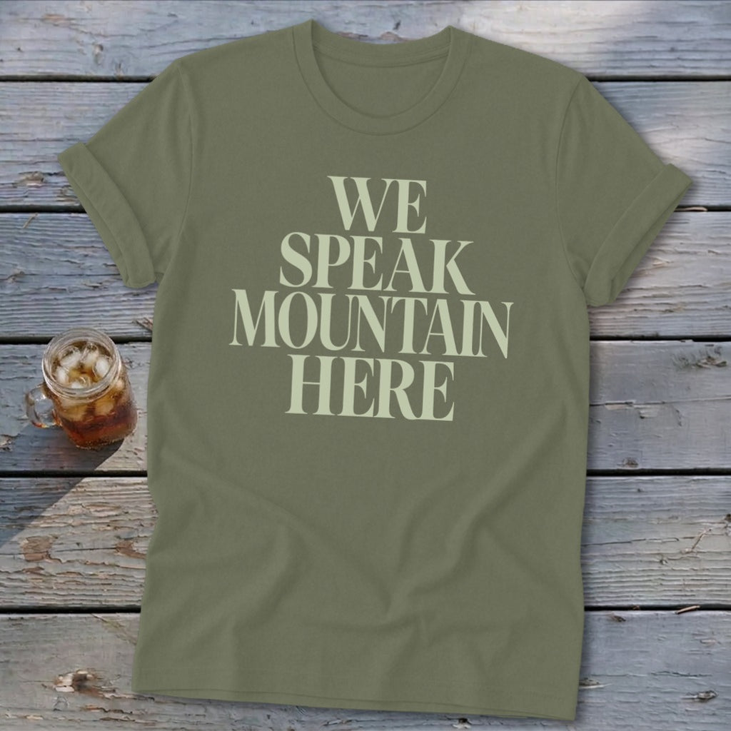 Olive green t-shirt with "WE SPEAK MOUNTAIN HERE" text and a glass of iced tea.