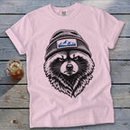 Pink t-shirt with a black ink drawing of a raccoon wearing a beanie with mountains.