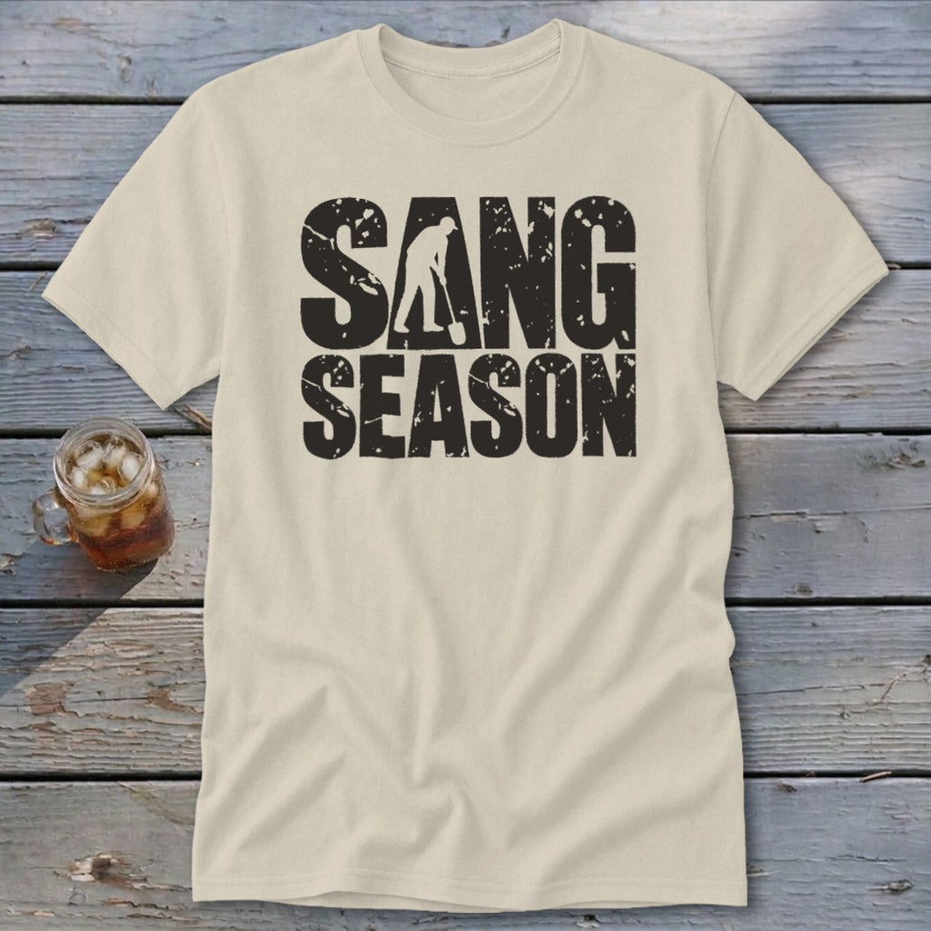 A cream-colored t-shirt with distressed black text reading SANG SEASON and a silhouette of a person digging.