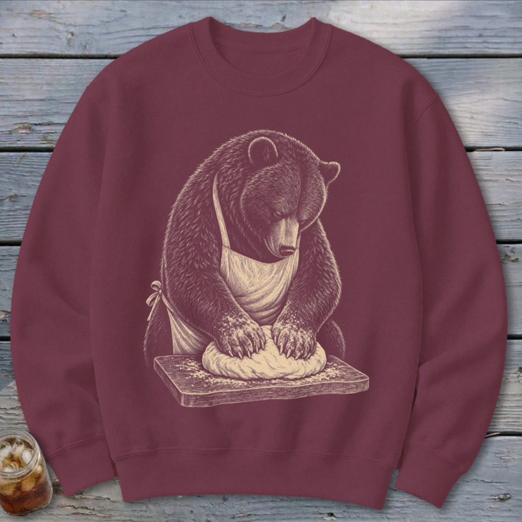 Bear wearing apron kneading dough on wooden board graphic on maroon sweatshirt.