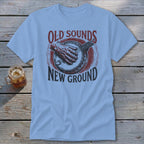 A light blue t-shirt featuring a red and dark blue banjo graphic with the text Old Sounds New Ground.