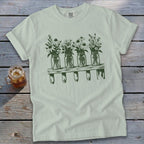 A sage green crewneck t-shirt featuring a dark green graphic of four mason jars filled with wildflowers resting on a wooden shelf.