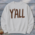 White crewneck sweatshirt with brown "Y'ALL" text on chest.