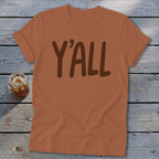 Brown t-shirt with "Y'ALL" text in dark brown, on a wooden surface.