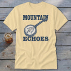 Cream-colored t-shirt with blue text reading MOUNTAIN ECHOES and an illustration of a banjo.