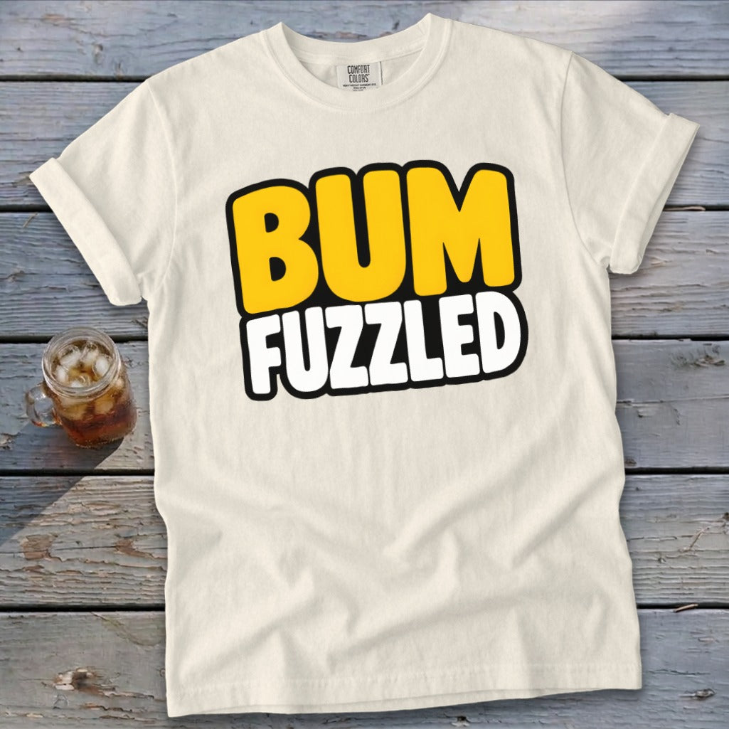 Off-white short-sleeve t-shirt with the words BUM FUZZLED printed in bold, yellow and white cartoon letters.