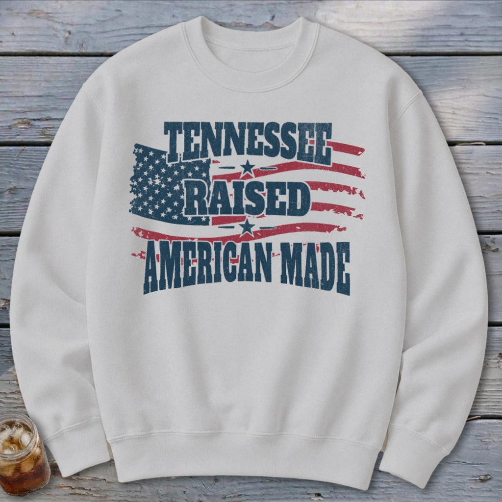 White sweatshirt with distressed American flag and text "TENNESSEE RAISED AMERICAN MADE".