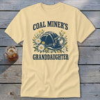 Pale yellow t-shirt with "Coal Miner's Granddaughter" text and a mining helmet graphic.