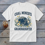 White t-shirt with "Coal Miner's Granddaughter" and a hard hat surrounded by flowers.