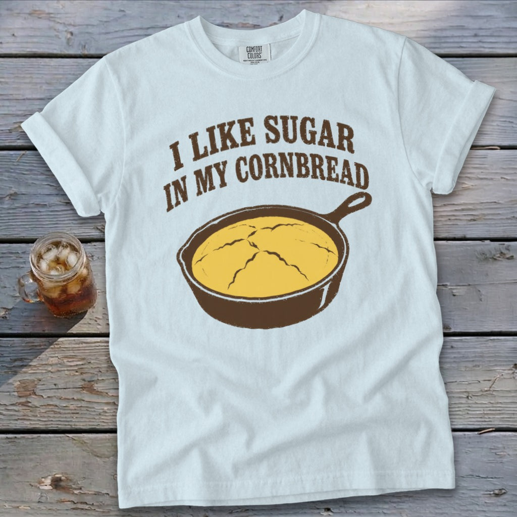 White t-shirt with brown text "I like sugar in my cornbread" and cast iron skillet with cornbread.