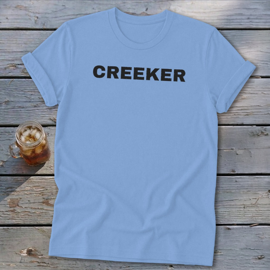 Light blue t-shirt with "CREEKER" text in black, next to a glass of iced tea.
