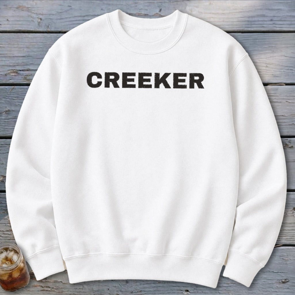 White sweatshirt with "CREEKER" text in black distressed lettering.