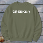 Olive green sweatshirt with white "CREEKER" text across the chest.