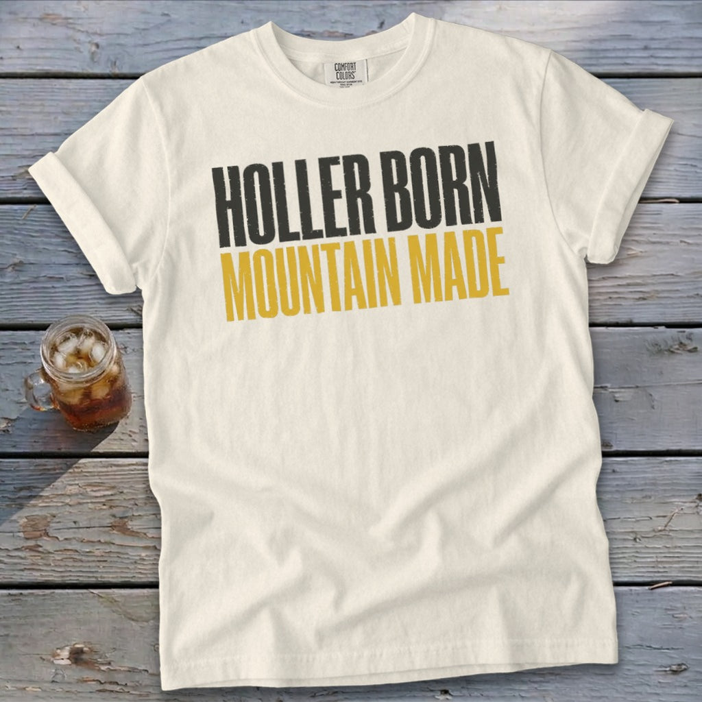 Cream t-shirt with black and gold text reading "Holler Born Mountain Made".
