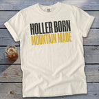 Cream t-shirt with black and gold text reading "Holler Born Mountain Made".