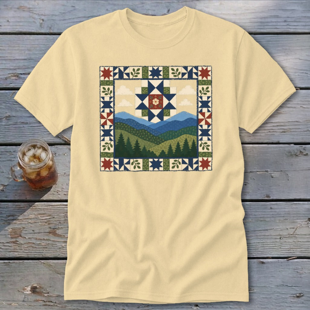 Light yellow t-shirt with a framed mountain, forest, and sky quilt design.