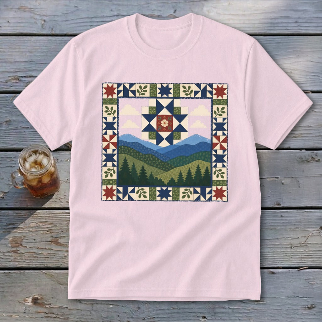 Pink t-shirt with a mountain landscape quilt-style graphic featuring trees and a star pattern.