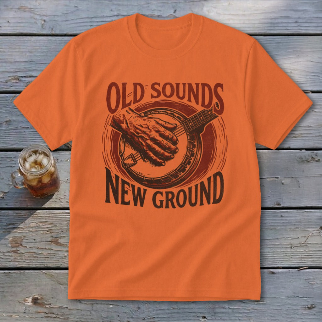 An orange t-shirt featuring a retro graphic of a banjo player and text reading Old Sounds New Ground.