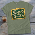 Sage green t-shirt featuring a vintage lighted sign graphic reading Dinner on the Grounds.