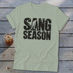 Sage green crewneck t-shirt featuring the distressed black text SANG SEASON and a silhouette of a person digging with a shovel.