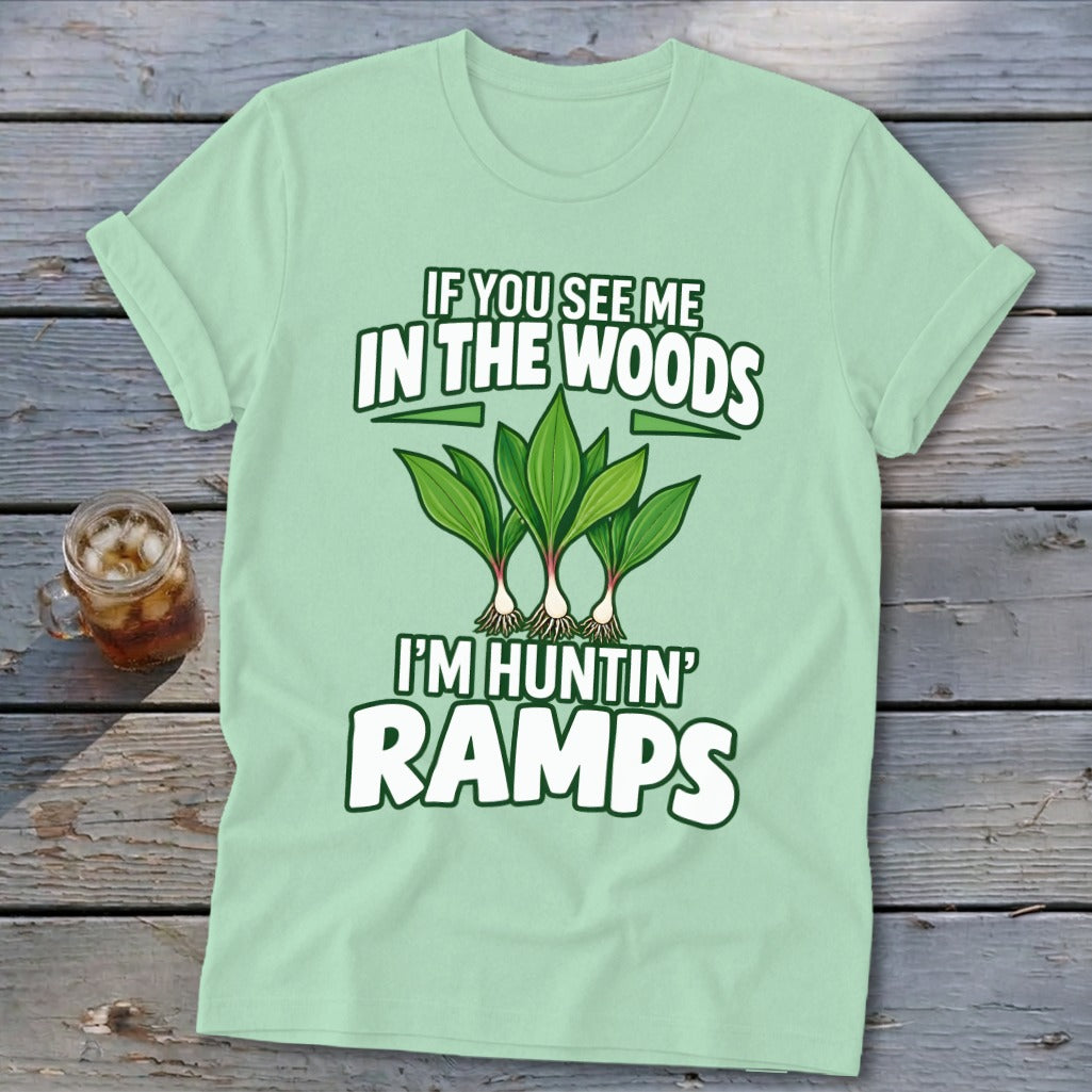 A light green t-shirt with text reading "IF YOU SEE ME IN THE WOODS I'M HUNTIN' RAMPS" and an illustration of ramps.