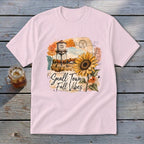 Pink t-shirt with "Small Town Fall Vibes" graphic featuring a sunflower and water tower.