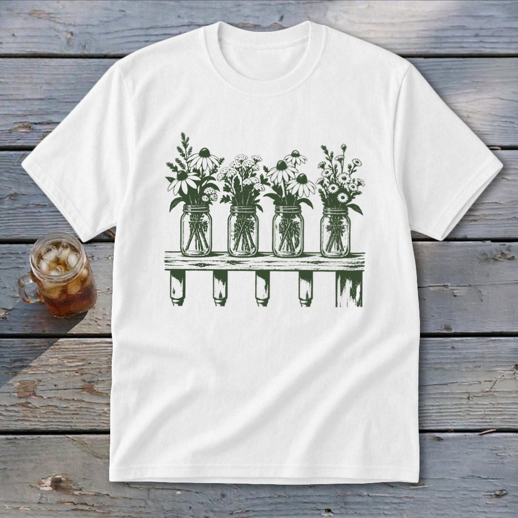 White t-shirt featuring a green botanical illustration of four mason jars filled with wildflowers on a shelf.