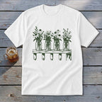 White t-shirt featuring a green botanical illustration of four mason jars filled with wildflowers on a shelf.