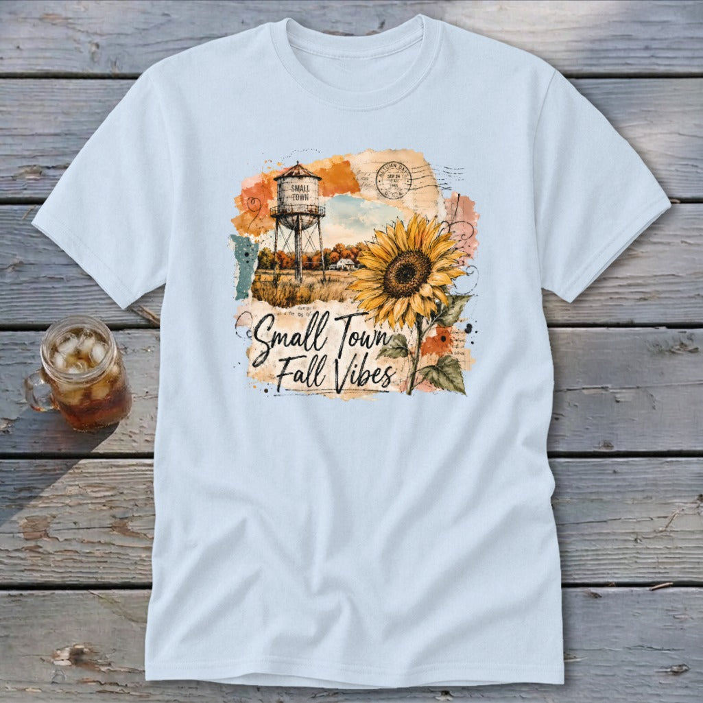 Light blue t-shirt graphic with sunflower, water tower, and text "Small Town Fall Vibes."