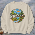 Cream sweatshirt with circular North Carolina mountain landscape graphic.