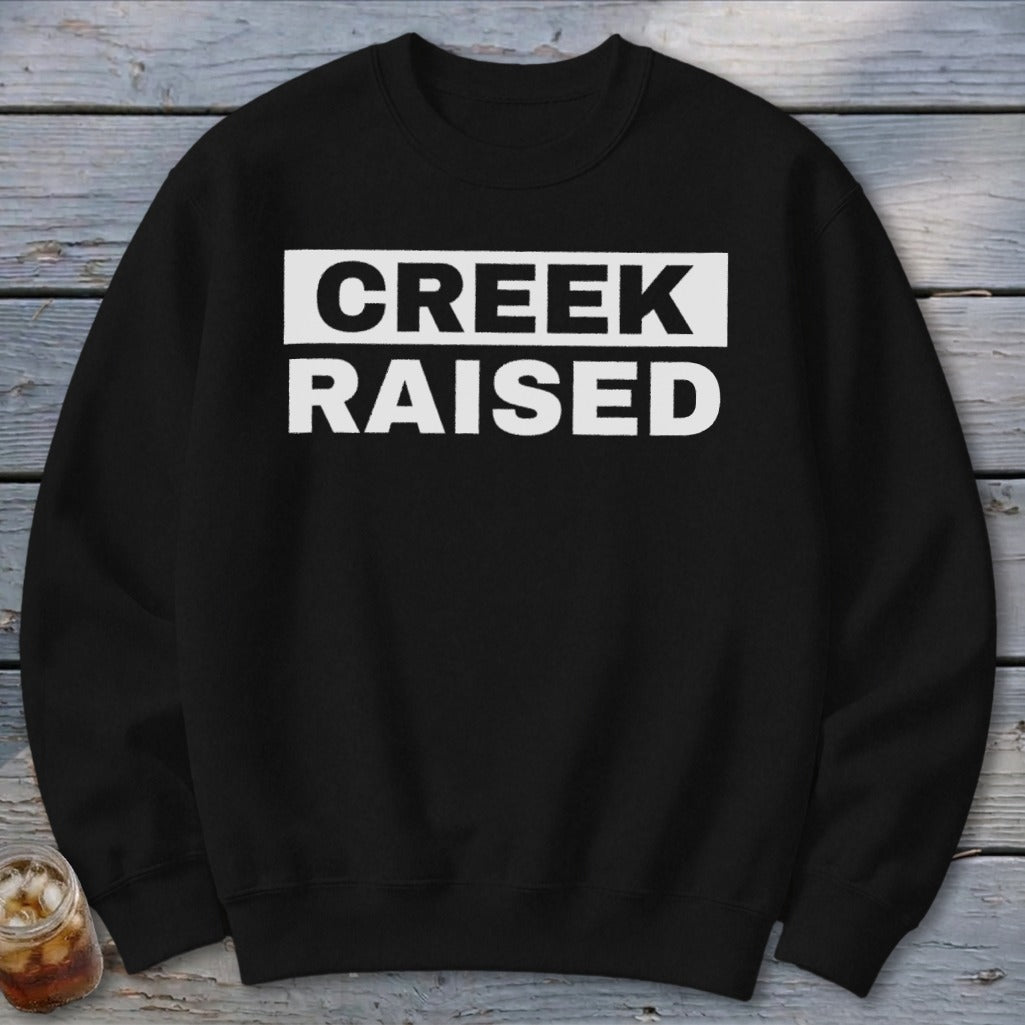Black sweatshirt with "CREEK RAISED" printed in white on the chest.