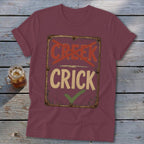 Maroon t-shirt with "CREEK" crossed out and "CRICK" checked off.