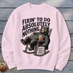 Light pink crewneck sweatshirt featuring a cartoon bear relaxing in a rocking chair with text.