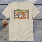 A cream-colored t-shirt with a vintage graphic of three quilts hanging on a clothesline.