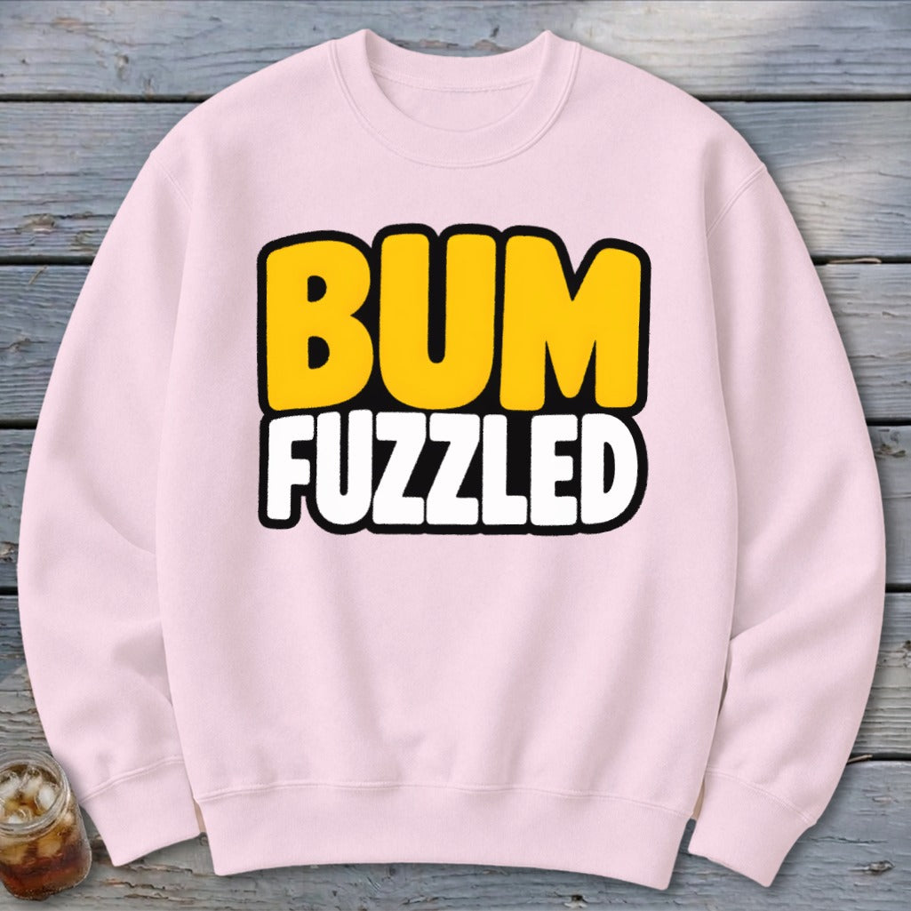 A light pink crewneck sweatshirt featuring the text BUM FUZZLED printed in bold, cartoonish letters.