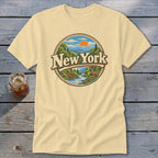 Light yellow t-shirt with circular New York landscape graphic featuring deer, river, and mountains.
