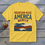 Yellow crewneck t-shirt with Mountain-Made America and 1776-2026 text above a patriotic mountain graphic.