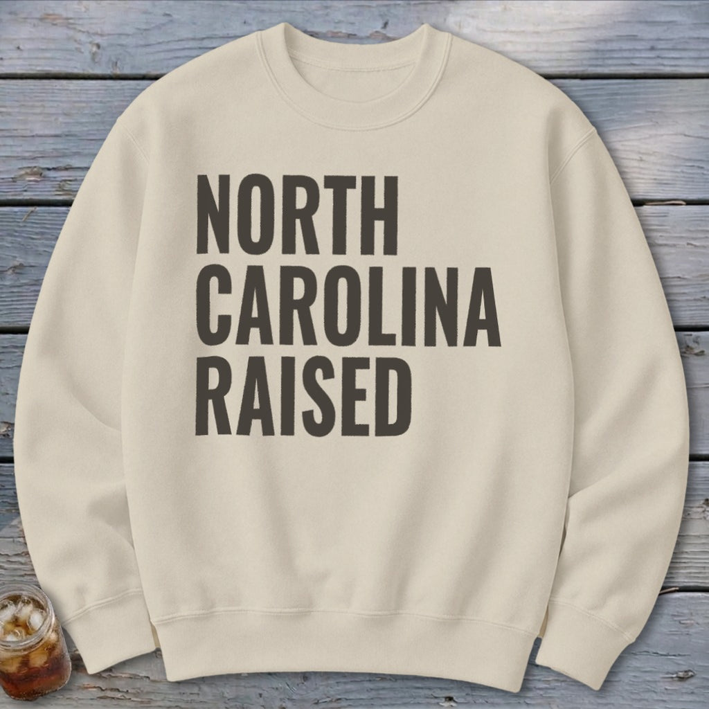 Cream sweatshirt with black text reading "NORTH CAROLINA RAISED".
