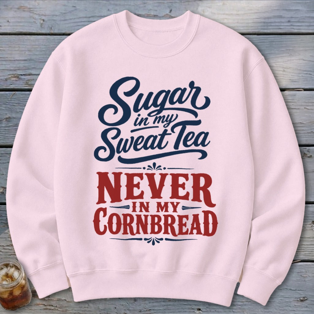 Light pink crewneck sweatshirt featuring blue and red text reading Sugar in my Sweet Tea, Never in my Cornbread.