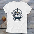 White t-shirt with "Appalachian Born and Bred Still Standing" text and mountain landscape graphic.