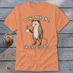 Peach t-shirt with possum holding coffee mug and text "Don't Mind Me, I'm Just Sulled Up."