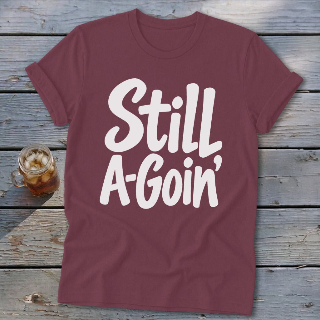 Maroon short-sleeve t-shirt with rolled cuffs and white text that reads Still A-Goin'.