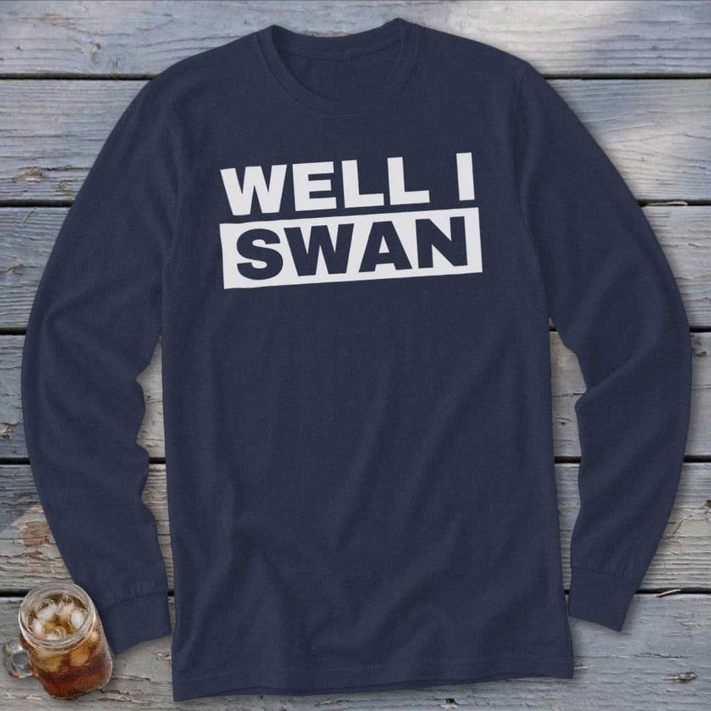 Dark blue long-sleeve t-shirt with white block text reading WELL I SWAN on a wooden background.