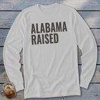 White long sleeve shirt with "ALABAMA RAISED" text in dark gray.