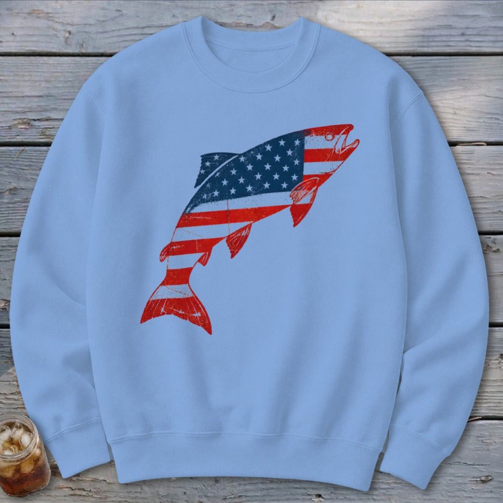 A light blue crewneck sweatshirt featuring a leaping fish graphic patterned with the American flag.