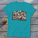 Teal t-shirt featuring a stylized graphic of a mountain landscape combined with quilt patterns.